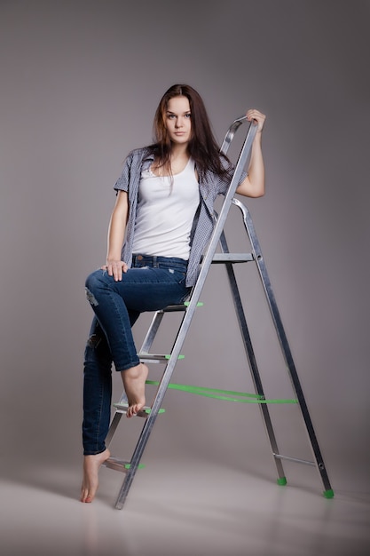 Young woman on step ladder. Isolated on white.