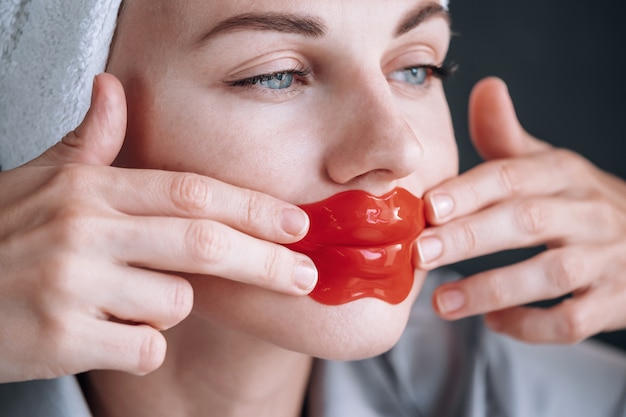 Young woman sticks a cosmetic mask on the lips.