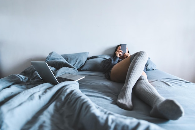 Young woman in stocking lay on bed and chat by phone.