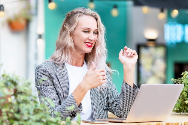 Giovane donna in un caffè di strada con un computer portatile.