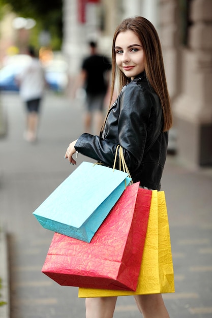 Young woman at the street with shopping with a raised foot