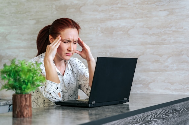 Giovane donna stressata e stanca con mal di testa seduto in ufficio