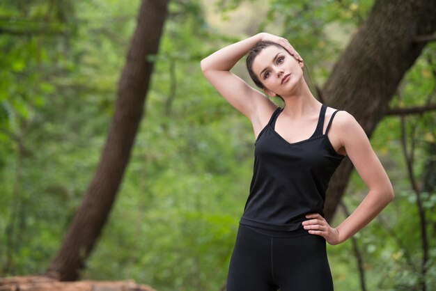 Young Woman Stretching Before Running In Wooded Forest Area  Training And Exercising For Trail Run Marathon Endurance  Fitness Healthy Lifestyle Concept