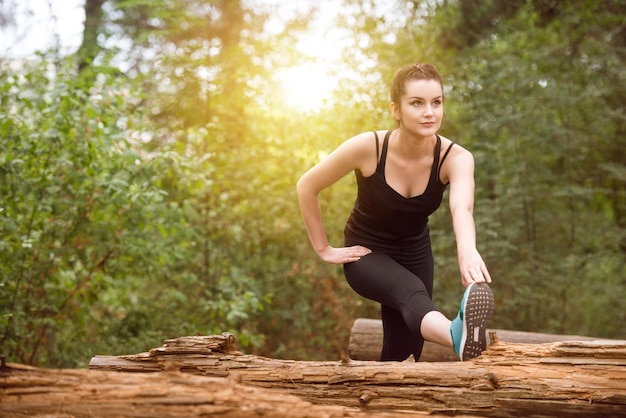 Young Woman Stretching Before Running In Wooded Forest Area  Training And Exercising For Trail Run Marathon Endurance  Fitness Healthy Lifestyle Concept