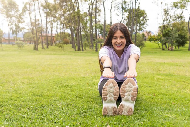 Young woman stretching her two legs in the park