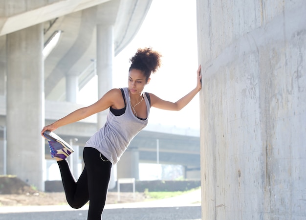 Photo young woman stretching leg muscles outdoors