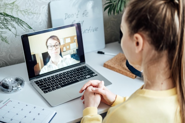 若い女性学生の応募者が、女性の人事担当者とオンラインで仮想ビデオ通話の面接会議を行う
