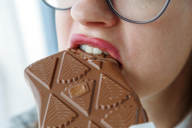 Foto giovane studentessa che mangia una barretta di cioccolato da vicino della bocca che mangia concetto di spuntino malsano