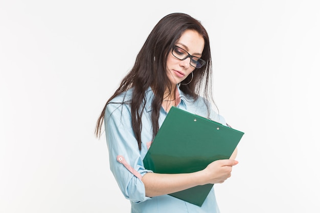 Young woman student with the green folder is standing on white wall