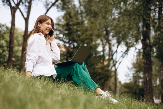 Young woman student working on laptop in park