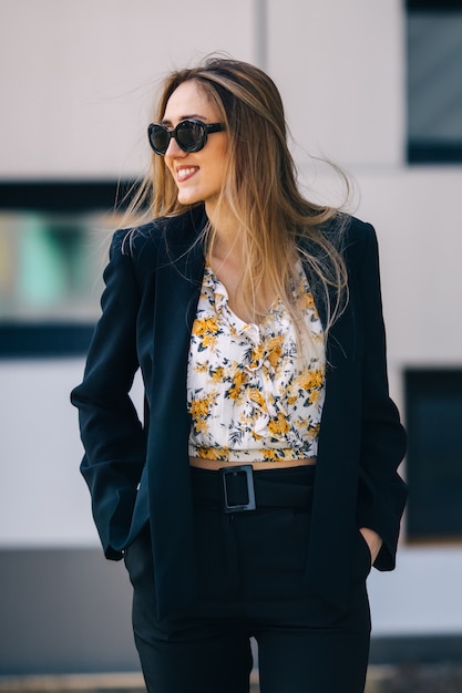 Young woman in a stylish black suit hold hands in her pockets