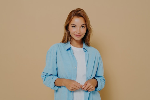 Young woman in stylish outfit posing on beige background