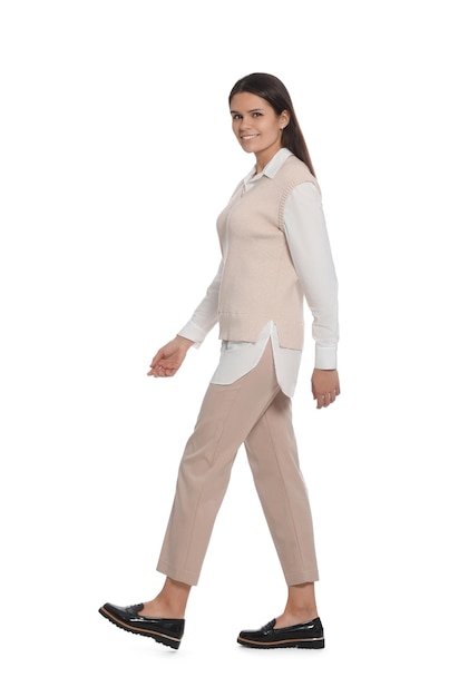 Молодая женщина в стильном наряде ходит на белом фоне
