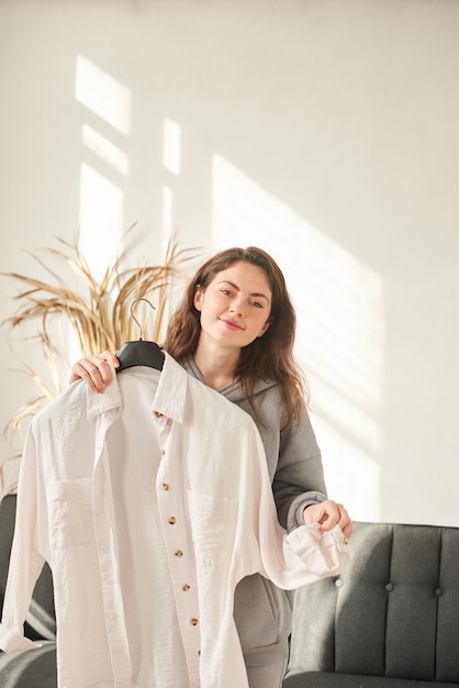 Young woman stylist chooses clothes in dressing room. shallow\
depth of field. vertical photo