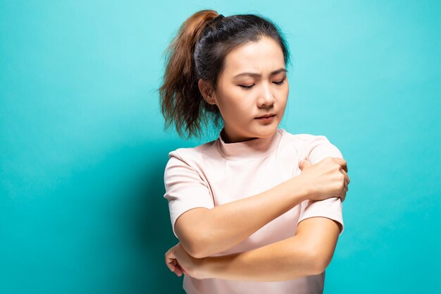 Photo young woman suffering from arm pain against turquoise background