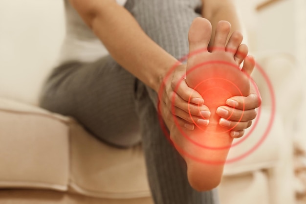 Young woman suffering from foot pain indoors closeup