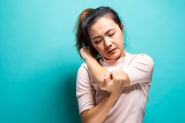 Photo young woman suffering from hand pain against turquoise background