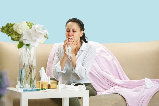 Фото Молодая женщина страдает от домашней пыли или сезонной аллергии чихает салфеткой