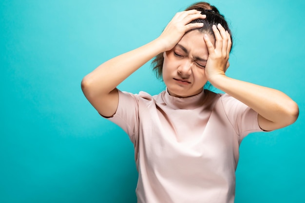 Photo young woman suffering from headache against turquoise background