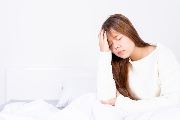 Young woman suffering from headache and sitting in bed