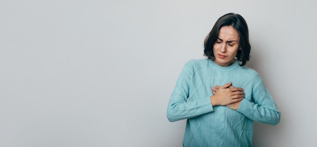 Young woman suffering from heart attack isolated on gray background