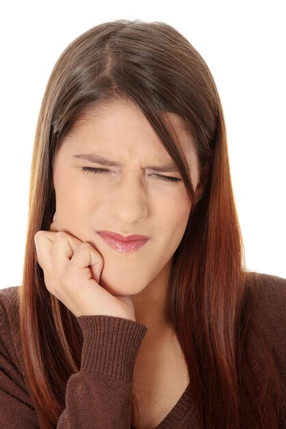白い背景に歯の痛みを抱えている若い女性