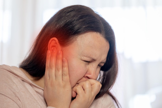 耳鳴りの不眠症やストレスの概念に苦しんでいる若い女性耳の痛みを持っている病気の女性