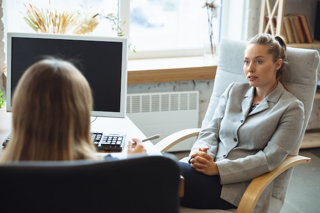 Young woman in suit sitting in office during the job interview with female employee