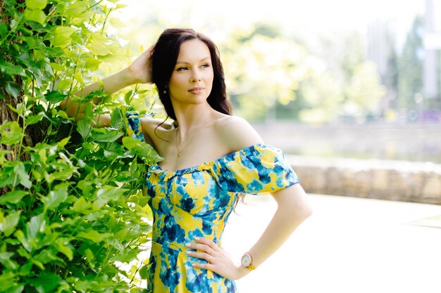 Young woman in summer dress is walking in green park and enjoying the sun playful and beautiful girl on warm sunny day