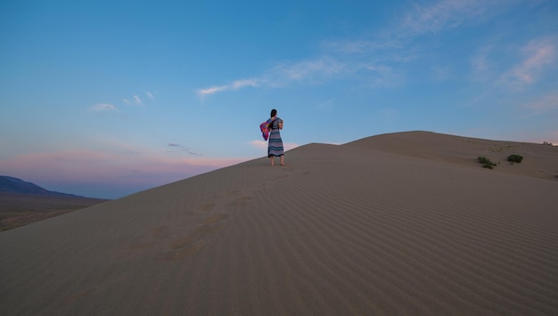 Young woman in a summer dress walking on desert dunes