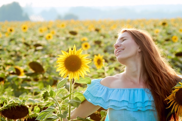 Young woman in sunflower field has fun