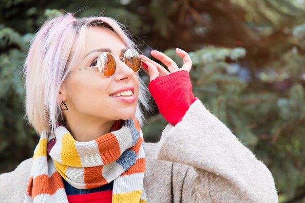 Foto giovane donna in occhiali da sole su uno sfondo di abete