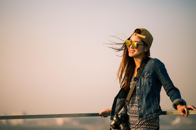 Young woman in sunglasses standing against sky