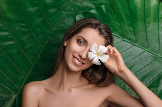 Young woman surrounded by tropical leaves