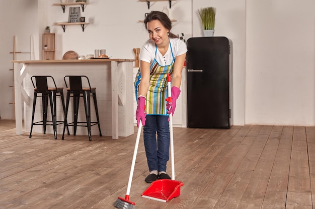 Young woman sweeping floor on the kitchen