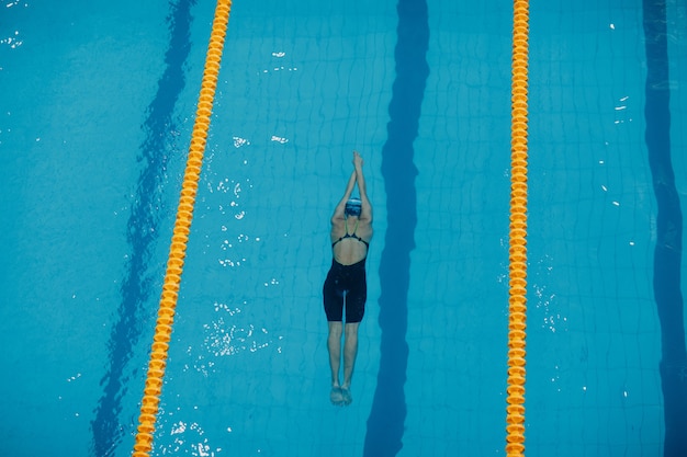 Young woman swimmer swims in swimming pool.