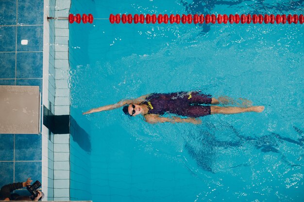 Young woman swimmer swims in swimming pool.