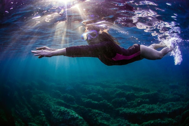 Young woman swimming in the ocean at sunset