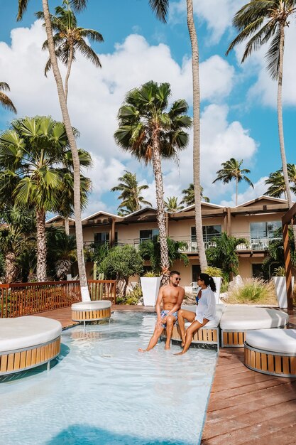 Photo young woman swimming in pool by palm trees against sky