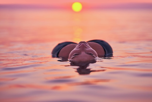 日の出の海で泳いでいる若い女性