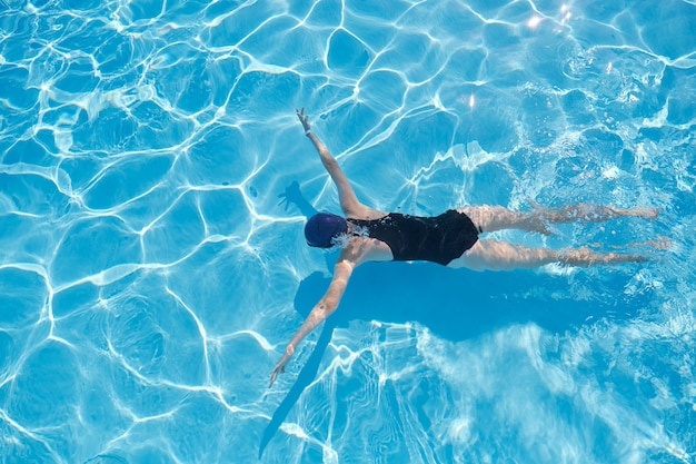 Young woman swimming underwater in an outdoor pool