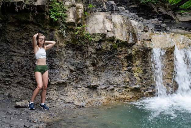Молодая женщина в купальнике, наслаждаясь водопадом