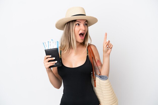 Young woman in swimsuit holding a passport isolated on white background intending to realizes the solution while lifting a finger up