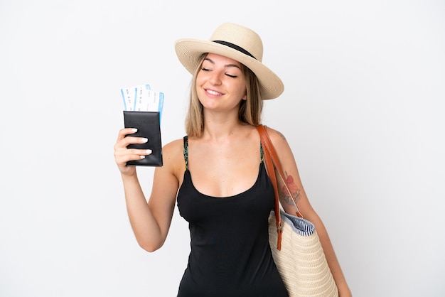 Young woman in swimsuit holding a passport isolated on white background with happy expression