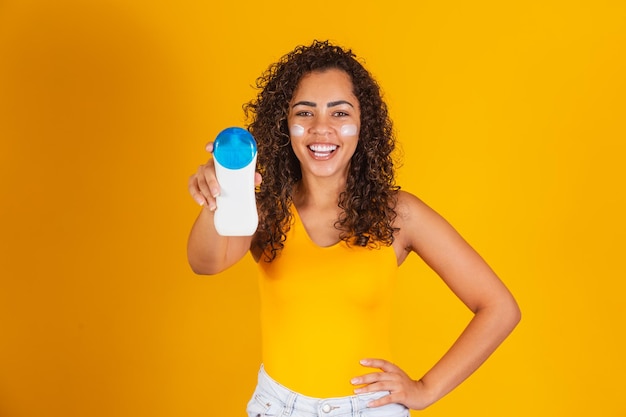 Young woman in a swimsuit holding a sunscreen.