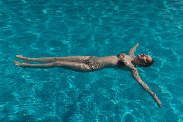 Young woman in swimsuit is swimming in pool