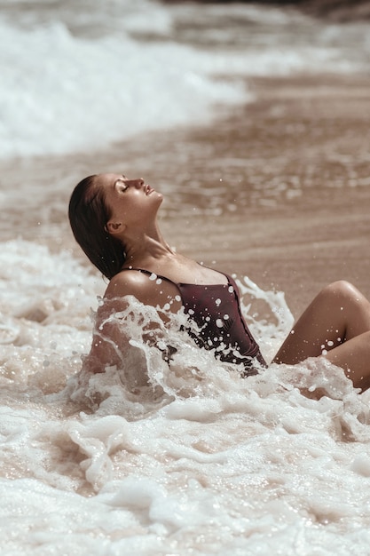 Giovane donna in costume da bagno in posa su una spiaggia