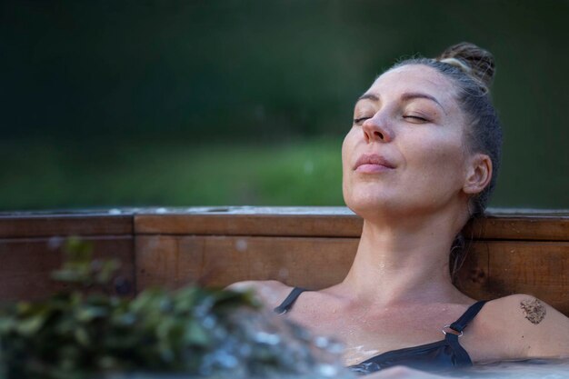 Foto una giovane donna in costume da bagno si siede in una vasca di sauna con erbe la bellezza gode di trattamenti acquatici spa e stile di vita sano closeup