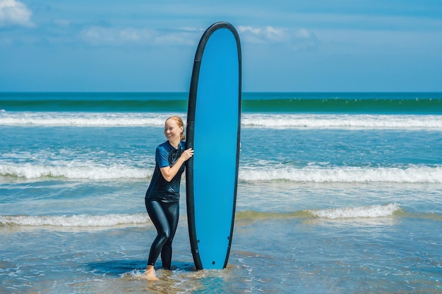 Young woman in swimsuit with surf for beginners ready to surf. Positive emotions.