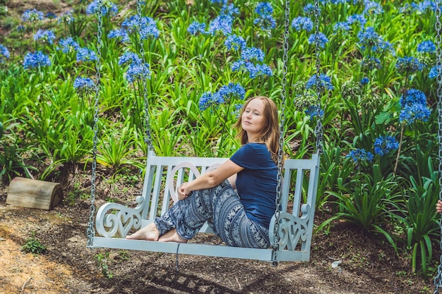 Young woman on a swing in a flower garden